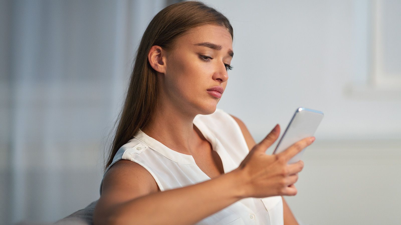 Woman sad, waiting by her phone for a guy to text.