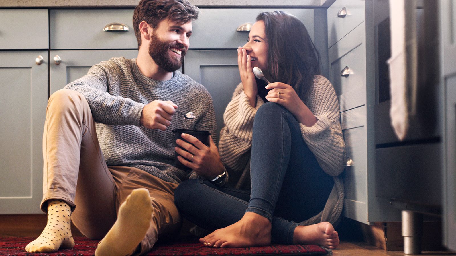 Husband and wife enjoying each other's company in the kitchen, laughing.