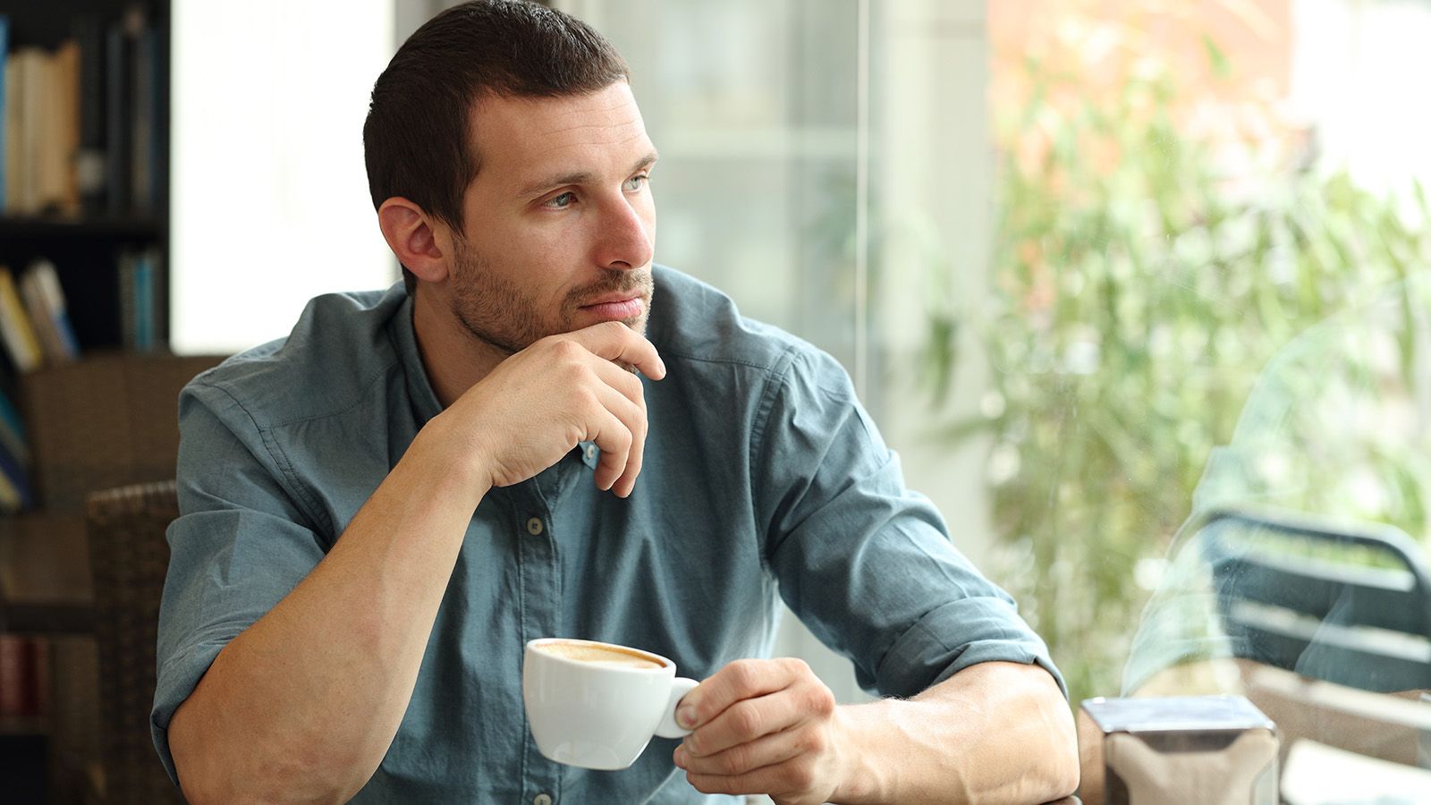 Middle aged man looking out window thinking about his marriage.