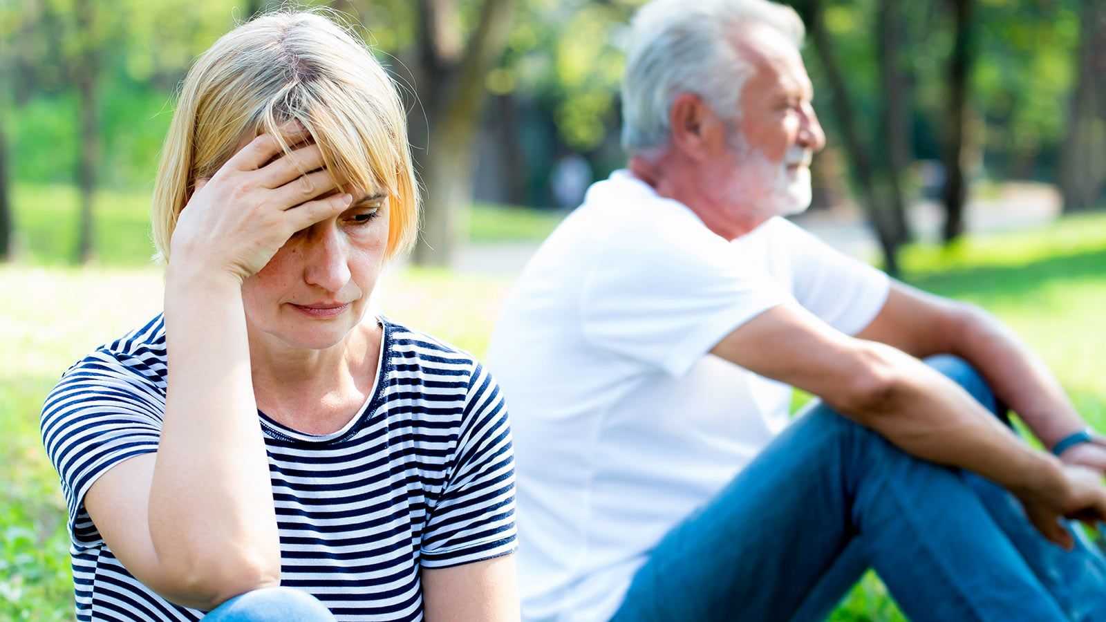 Older retired couple sitting in a park bored