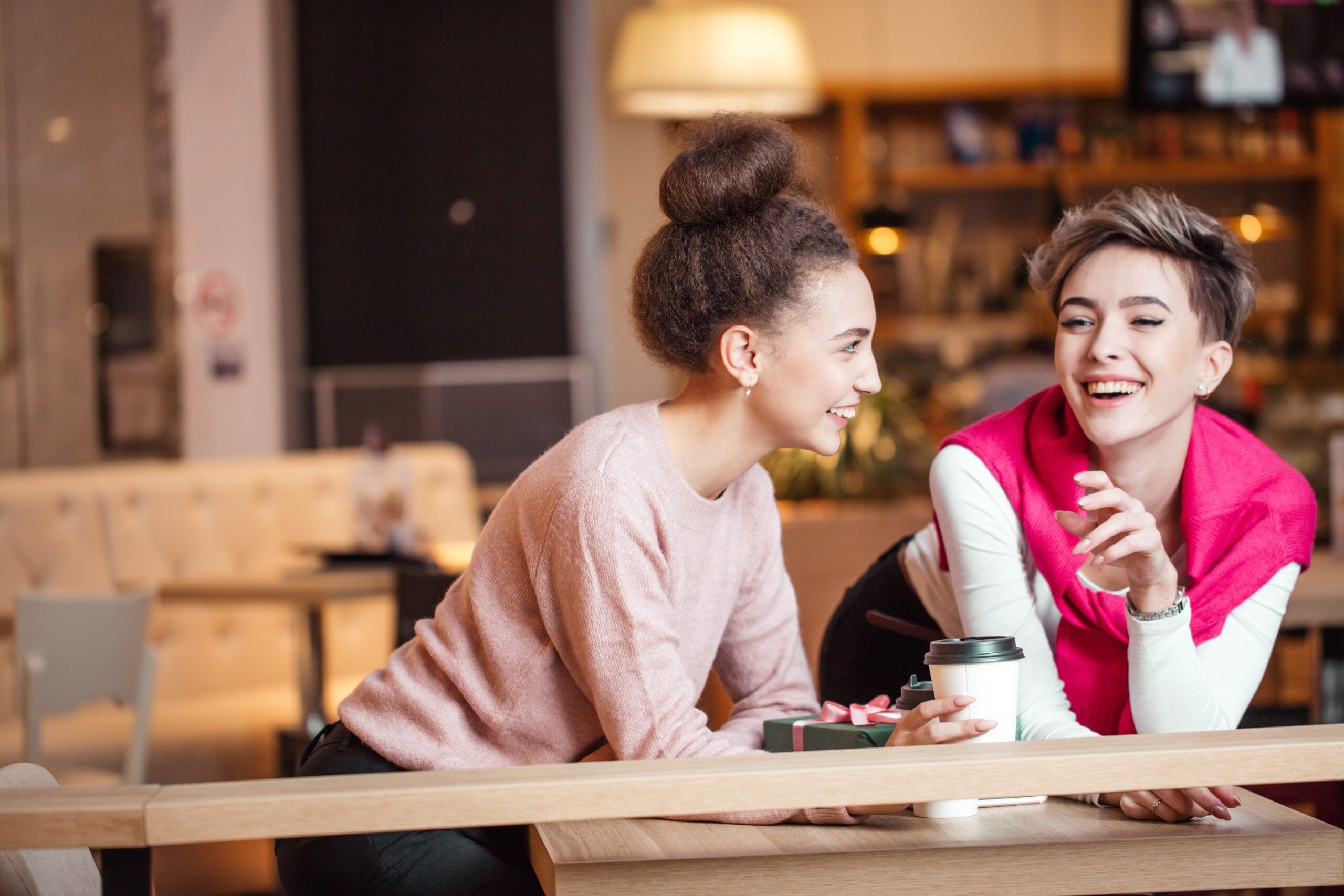 Two women speaking about another friend who isn't there.
