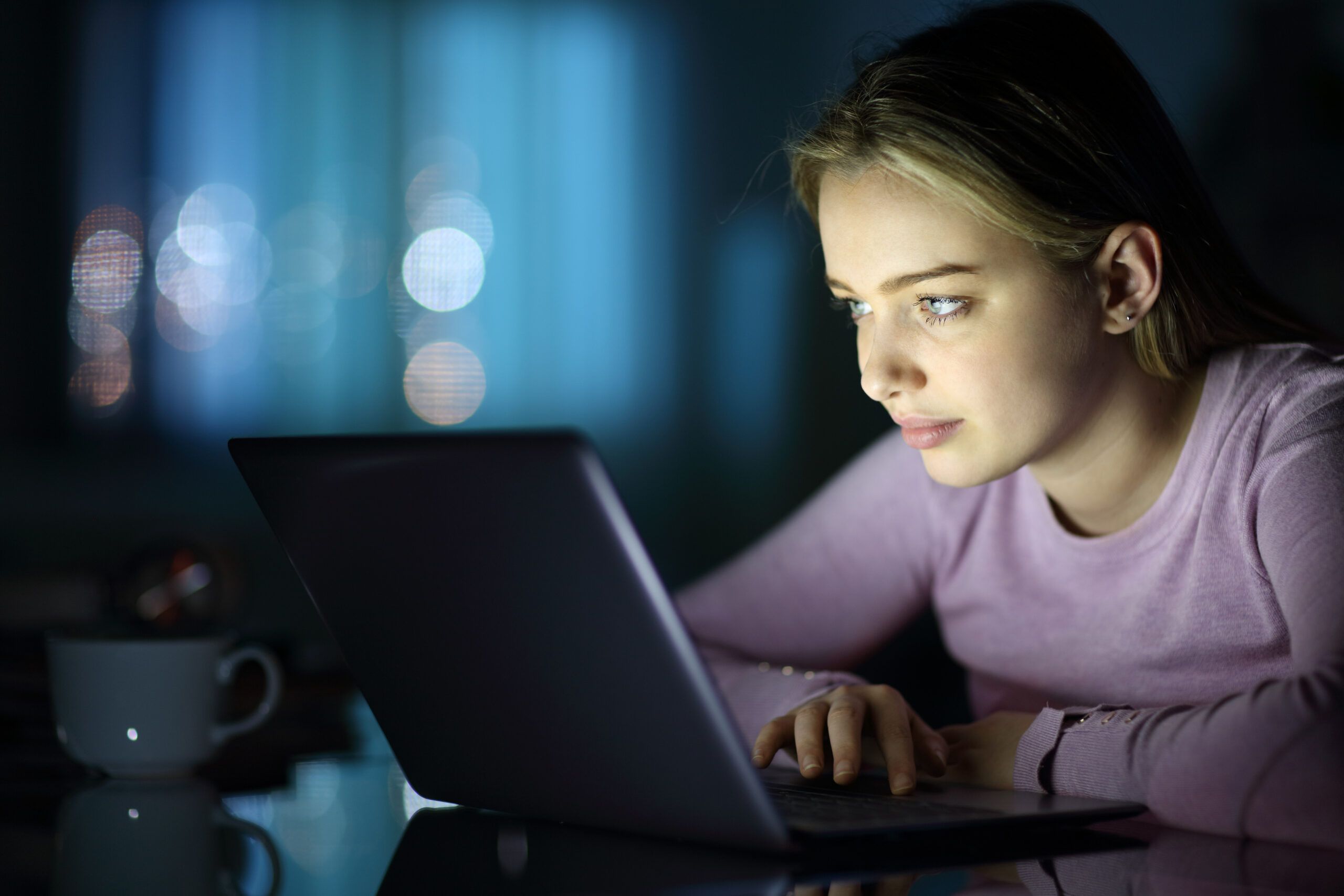 A woman answering work emails late at night.