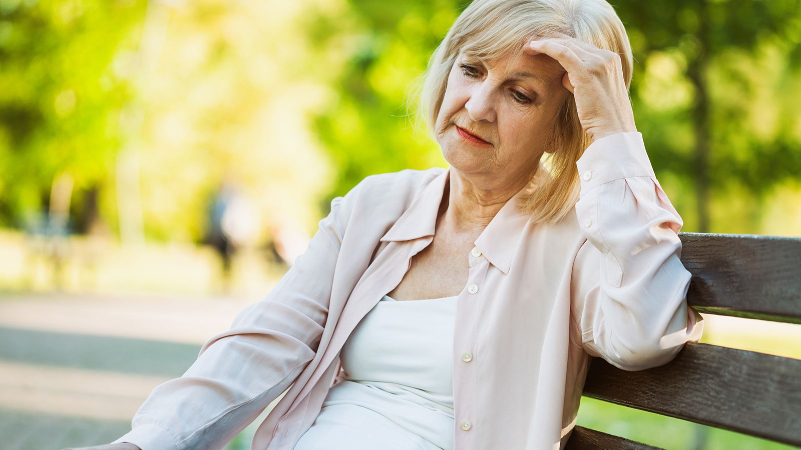 Lonely adult woman sitting in park in despair.