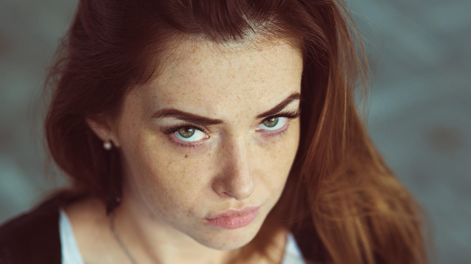 Closeup portrait. Red-haired girl with a serious facial expression looking at the camera