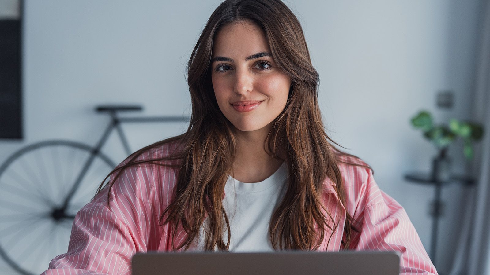 Happy young woman sit at desk look at laptop screen browsing surfing wireless Internet at home, smiling millennial female employee wor