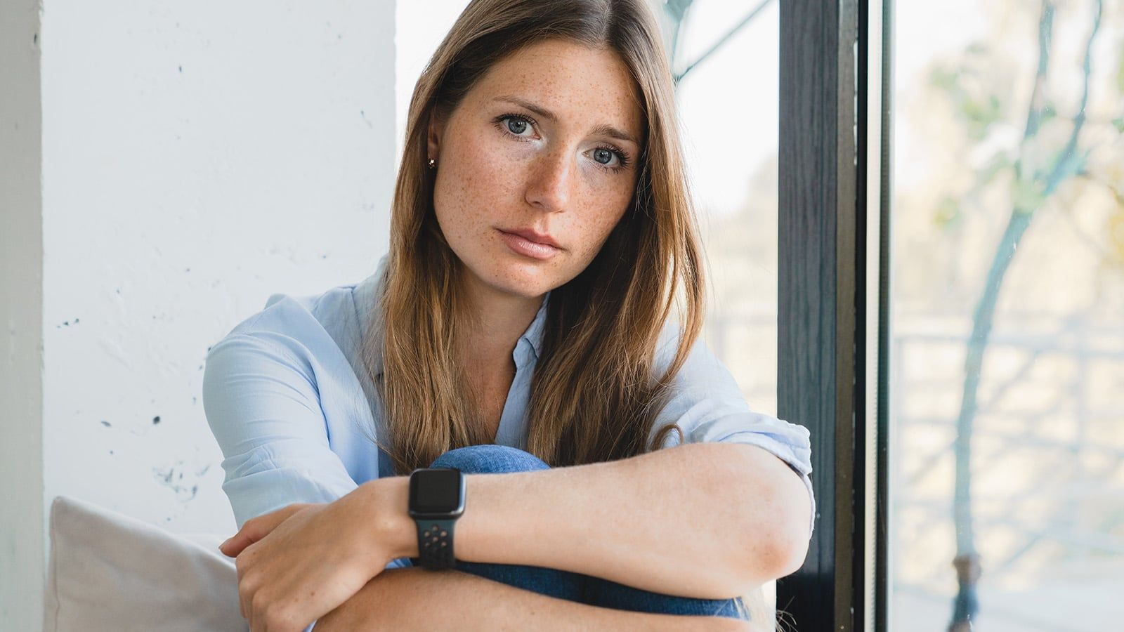 Worried young woman sitting by the window