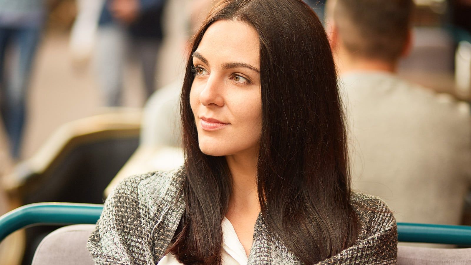 Photo of beautiful brunette woman focused aside, wrapped in coverlet, thinks about something with thoughtful expression