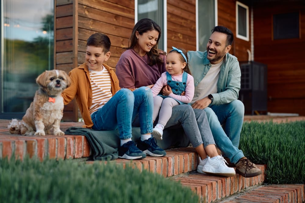 A happy family relaxing on the steps of the house with their dog