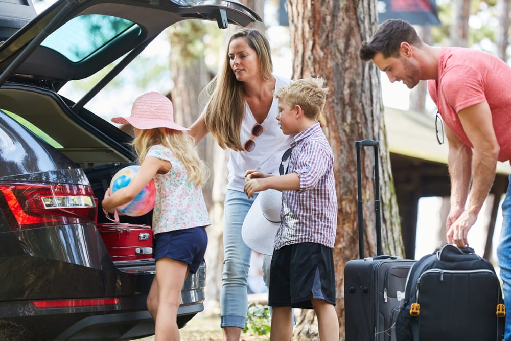 A family packing their bags into the trunk of a car for their vacation