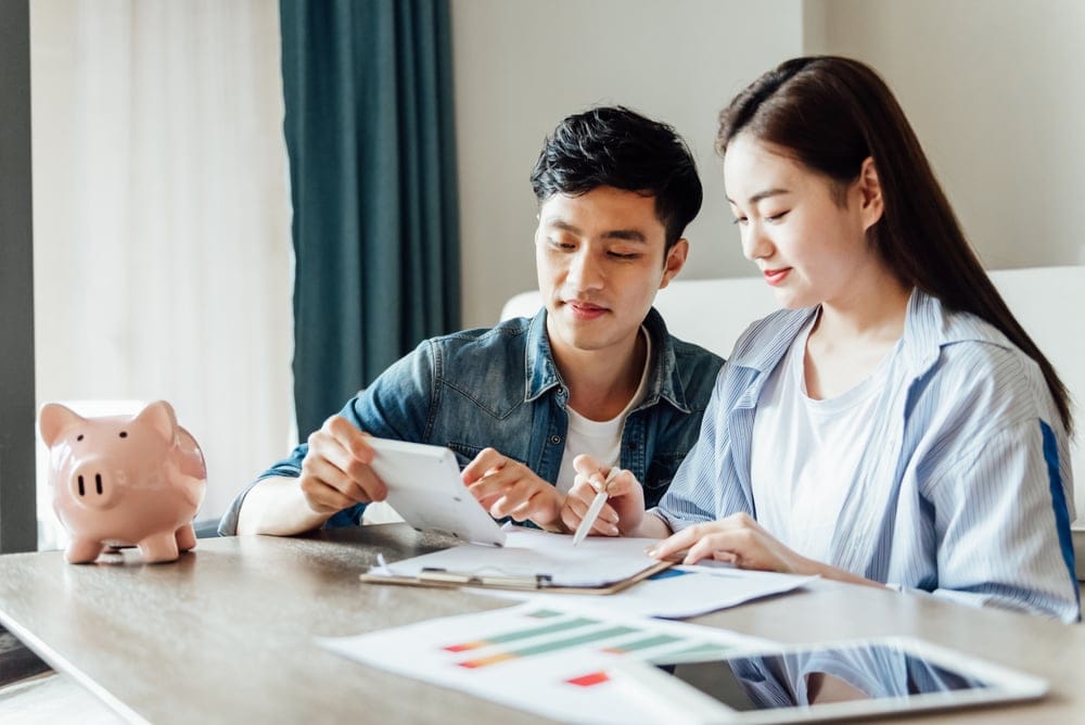 A young Asian couple sitting down and going through their bills