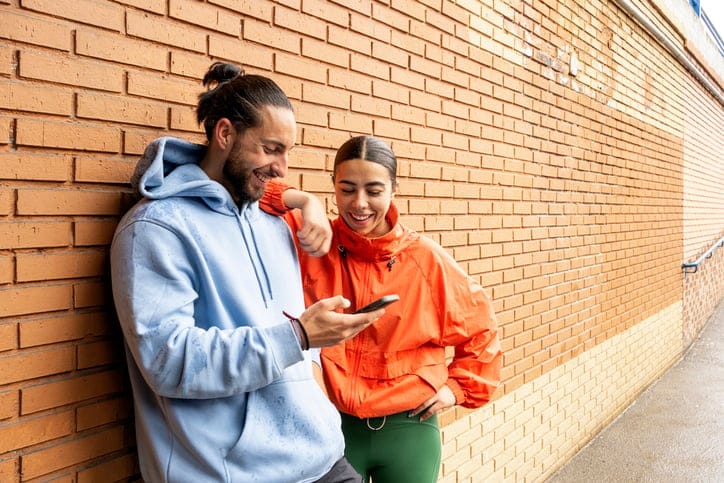 young couple looking at phone outdoors