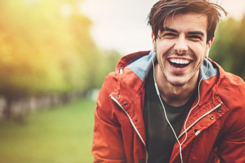 guy smiling in red coat at park