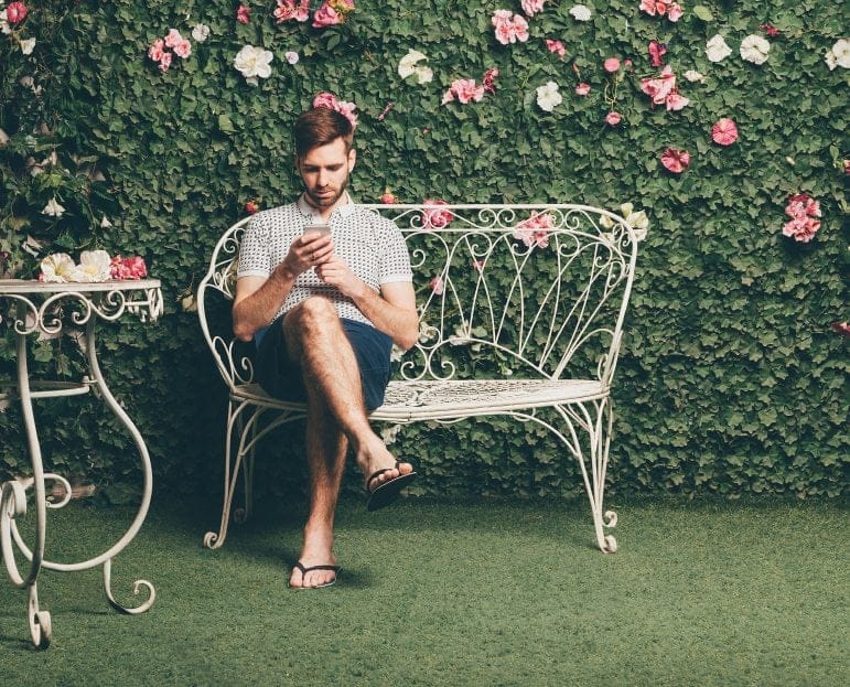 Man in flip flops on garden furniture.