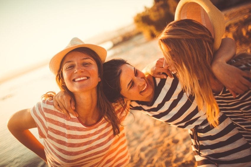 three female friends laughing on beach