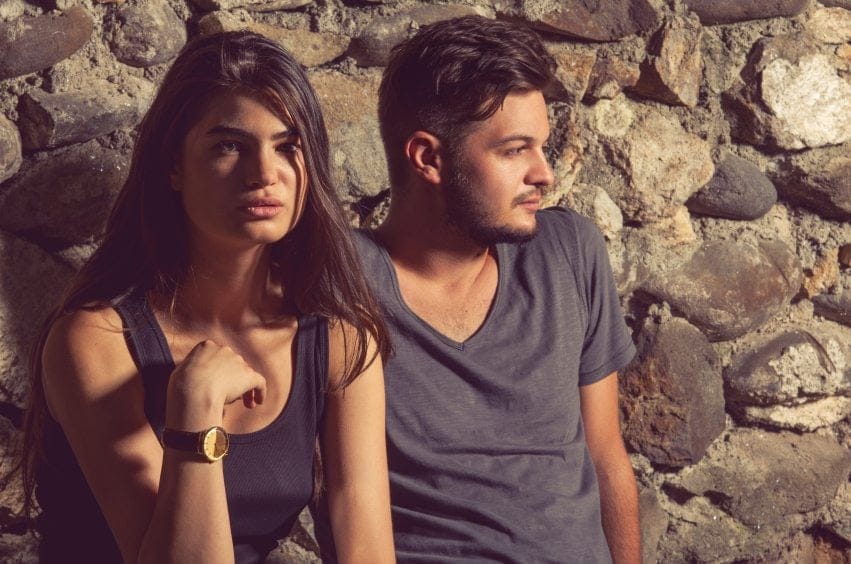 Couple posing against stone wall outdoors