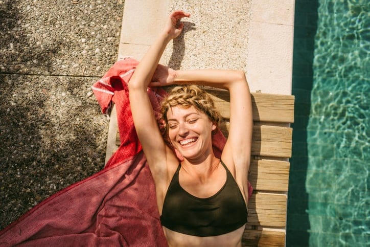 smiling woman laying poolside