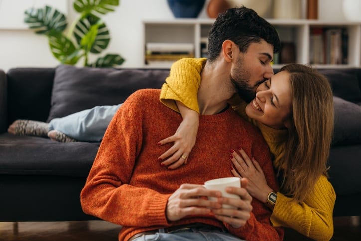 smiling couple cuddling in living room
