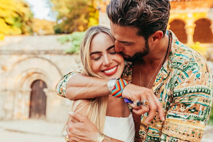 man kissing smiling girlfriend's cheek