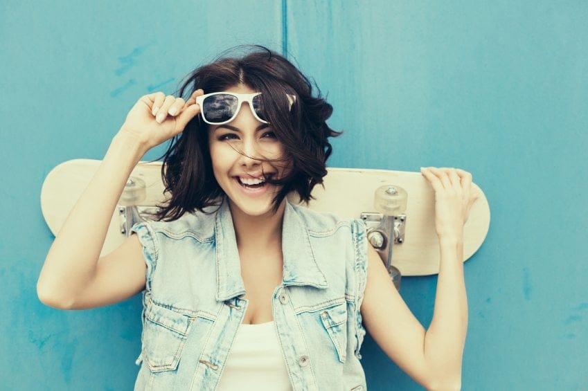 Young girl in sunglasses posing with skateboard
