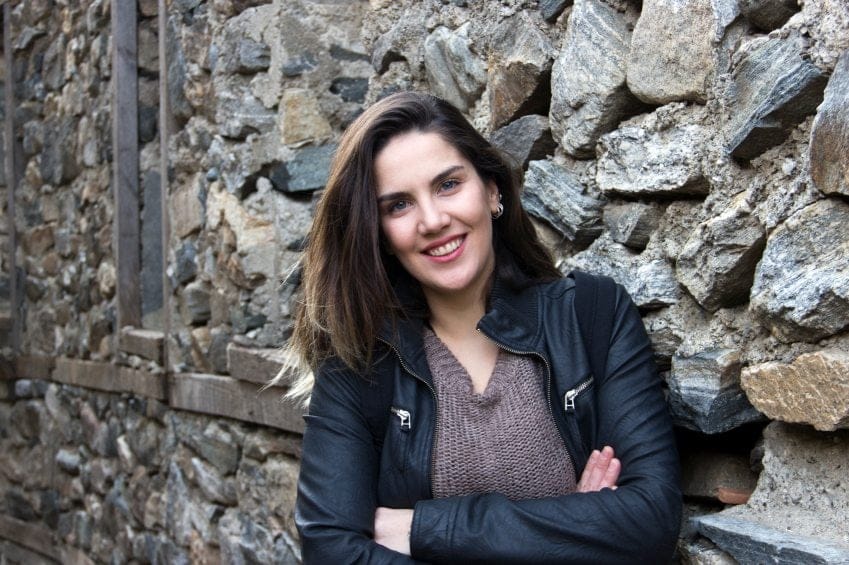 Brunette standing by wall smiling