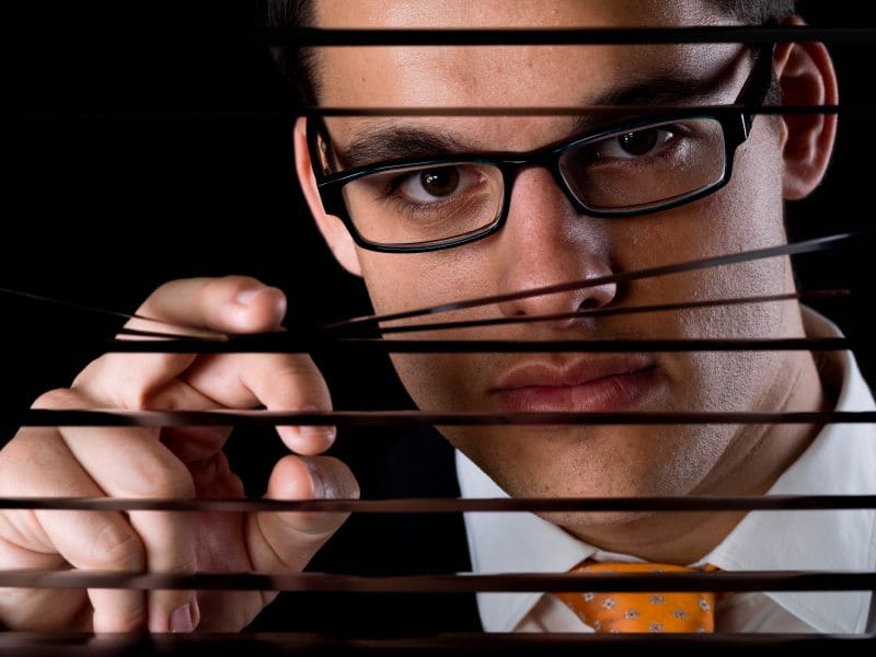 Guy peering through blinds