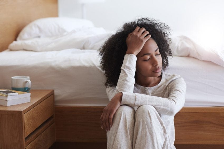 Afro American girl sat beside bed