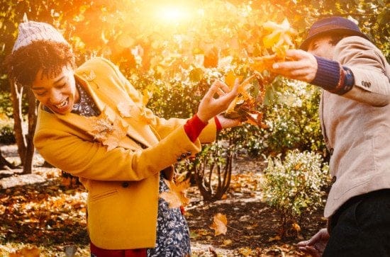 couple play fighting in autumn leaves
