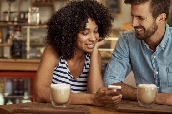 woman showing man text at coffee shop