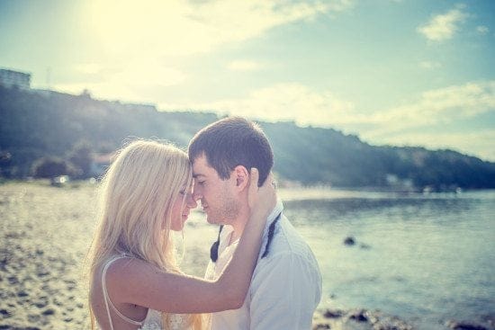 newlywed couple kissing on beach