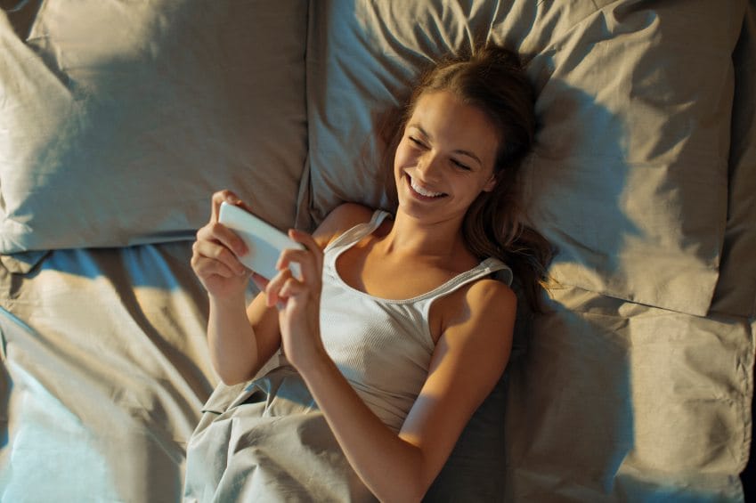 Girl laid in bed with smartphone