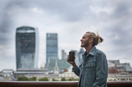 man with bun and coffee in city