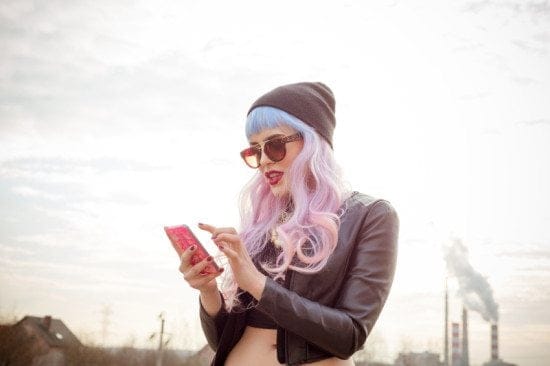 woman with pastel hair texting outside