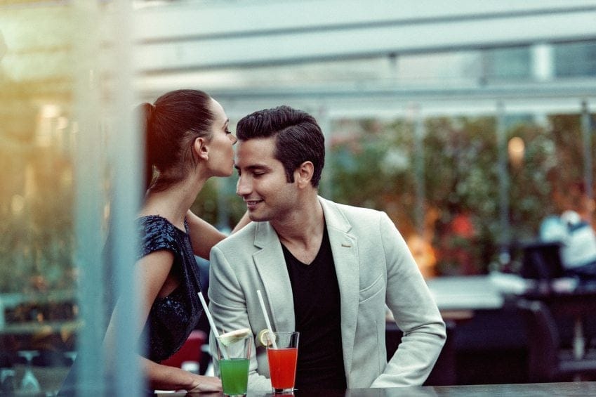 woman kissing man's head at bar