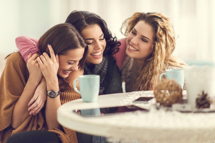 three happy women laughing coffee shop