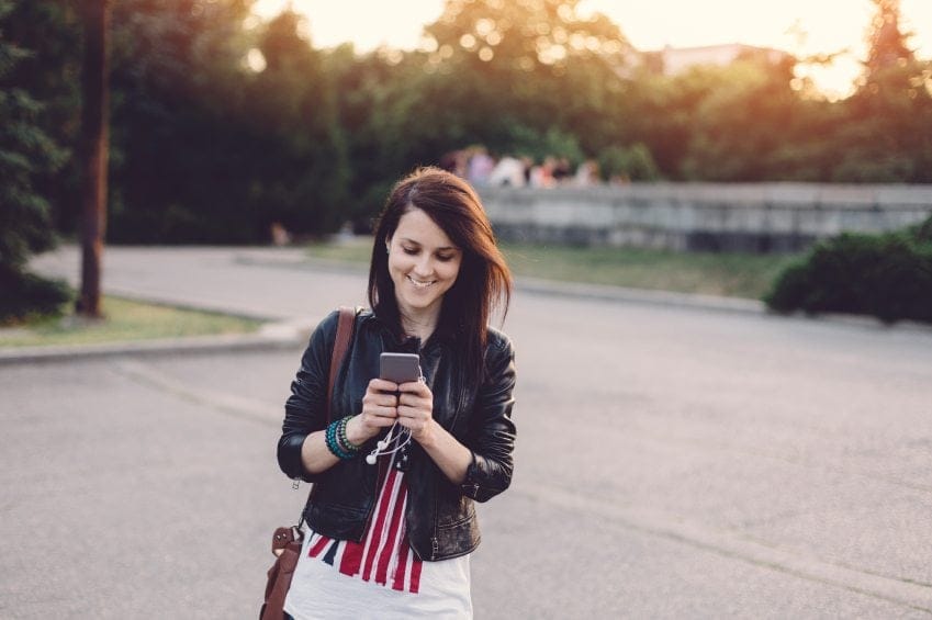 smiling girl texting while walking