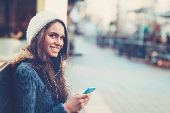 smiling woman texting outdoors in winter