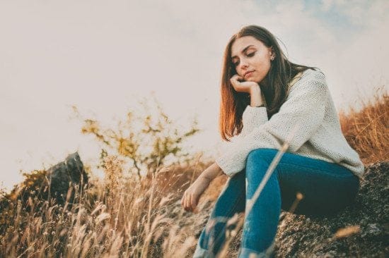 sad woman sitting in hay