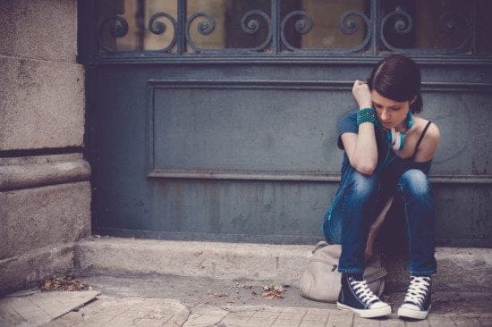 sad woman sitting on city curb