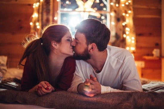 couple kissing at nighttime in bed