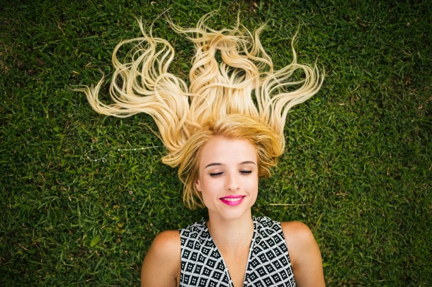 woman with blonde hair lying in grass