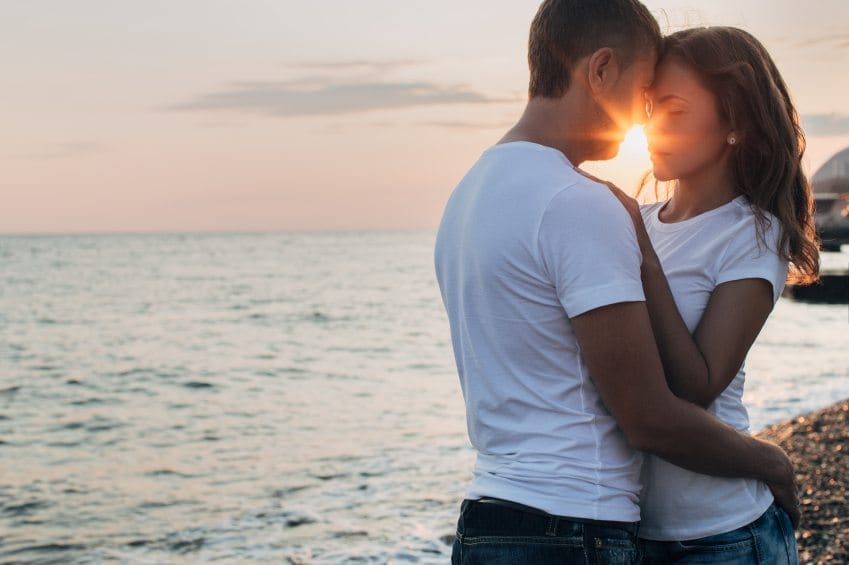 Woman and man embracing sunset beach.