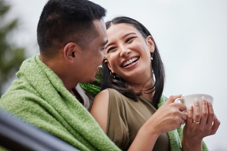 Young couple relaxing with blanket in outdoors.