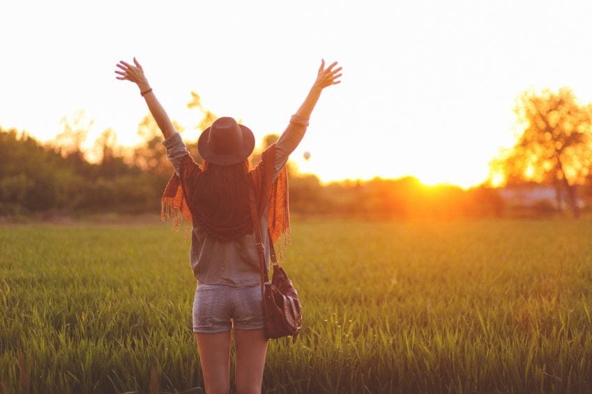 happy woman sunset field hands up