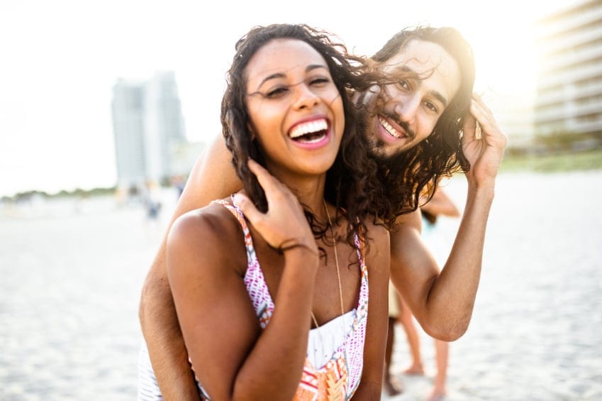 Black couple laughing on beach