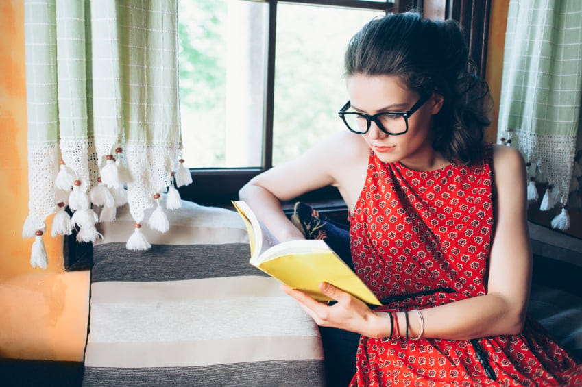 woman reading book home window