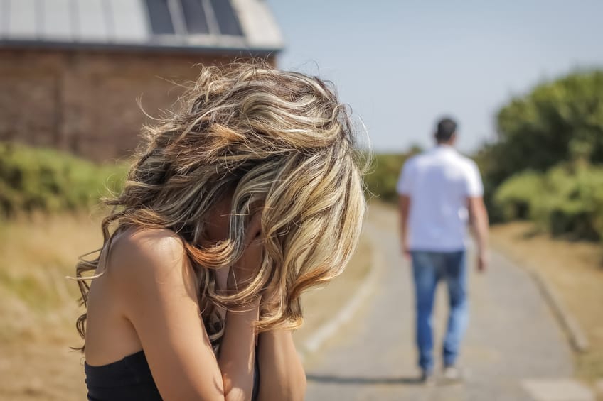Man leaving and woman with face on hands after a quarrel