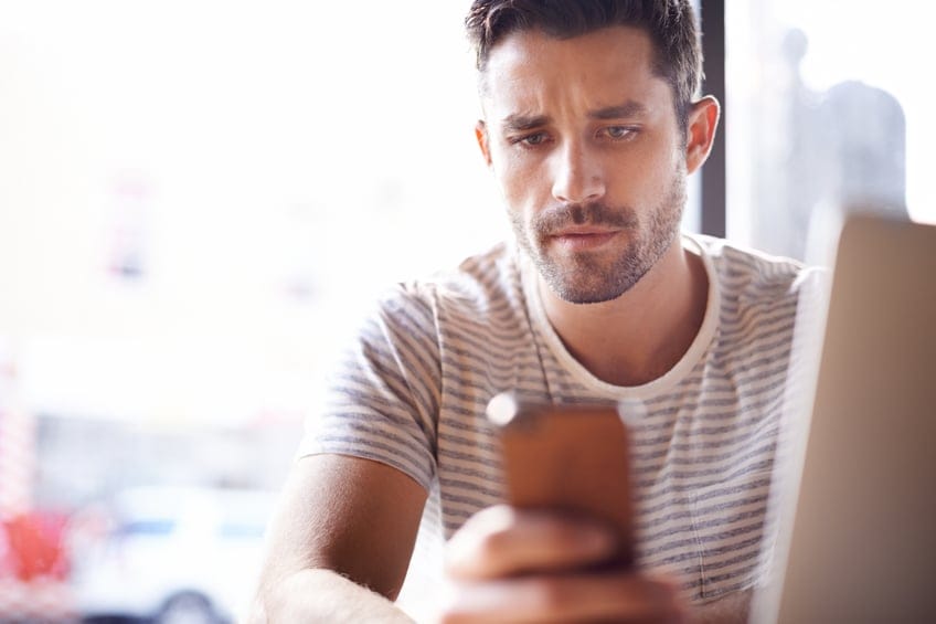 Shot of a young man using his phone in a cafe