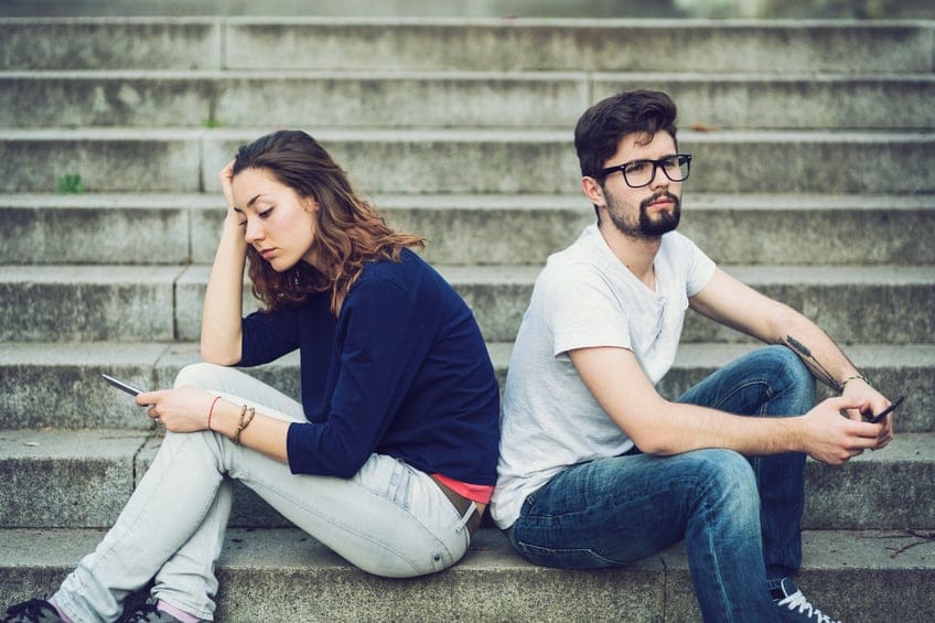 Couple ignoring each other while sitting on stairs back to back