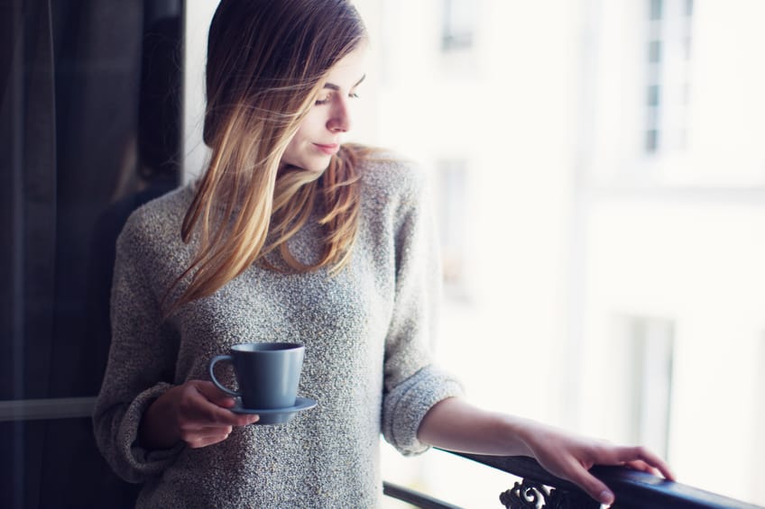 Woman with coffee looking out window