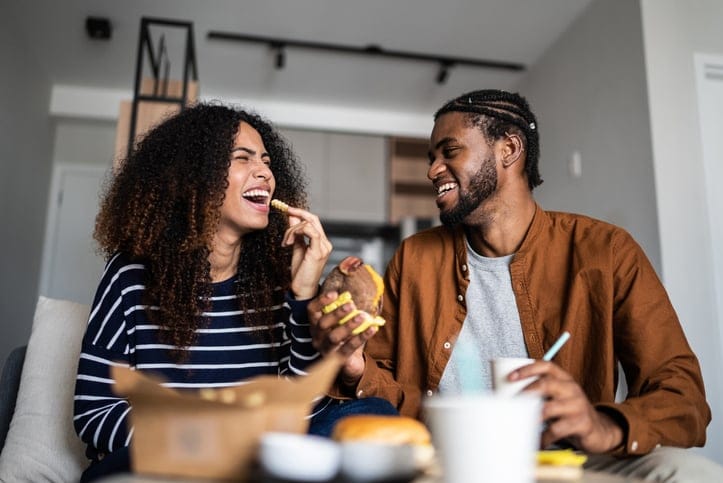 Happy couple eating fast food together.